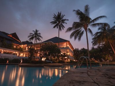 Luxurious tropical resort with swimming pool and palms at dusk, perfect for a tranquil vacation.